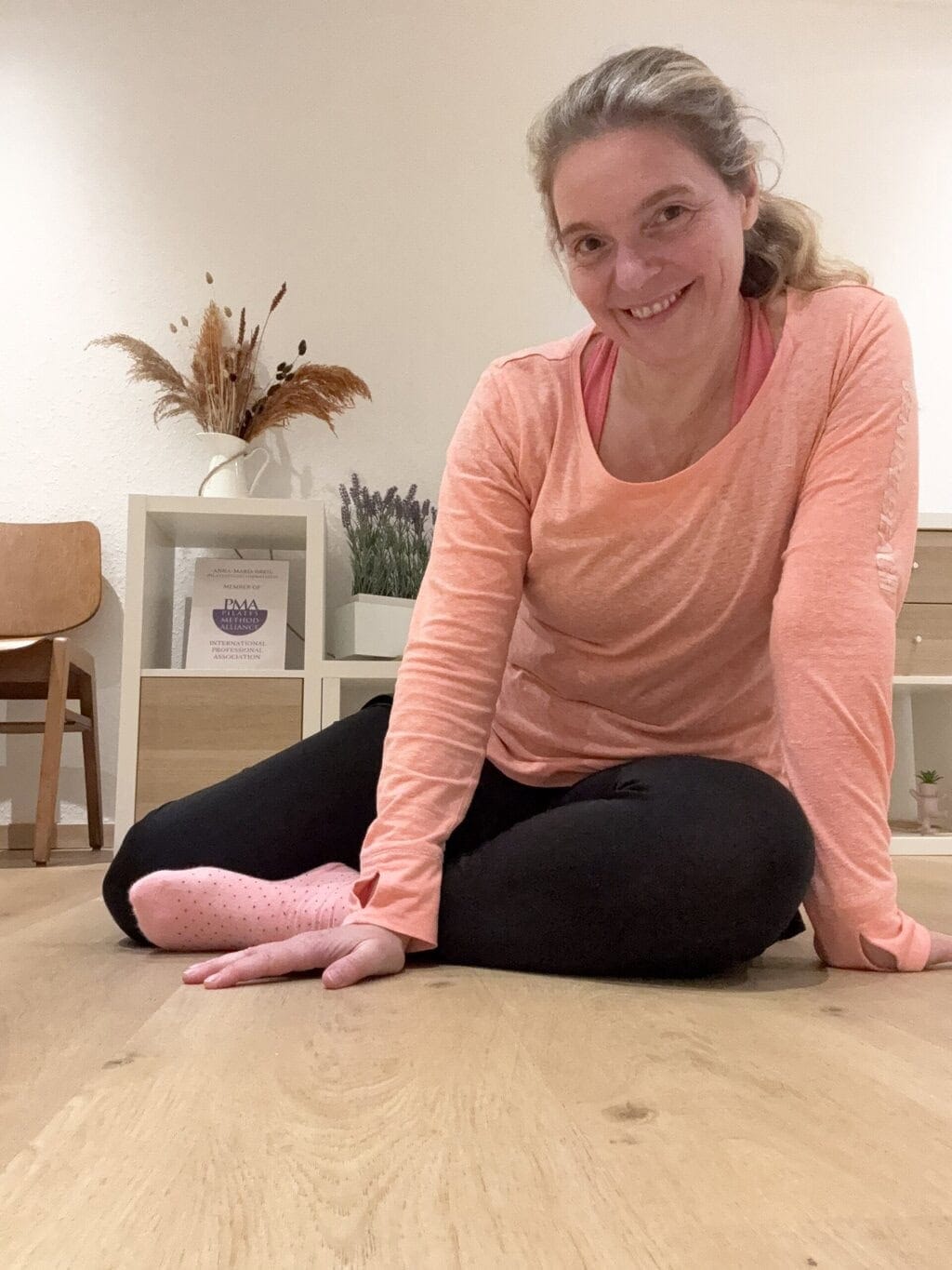 Pilates Anna Pilates Anna sitzt im Pilatesstudio im im Vorraum auf dem Boden